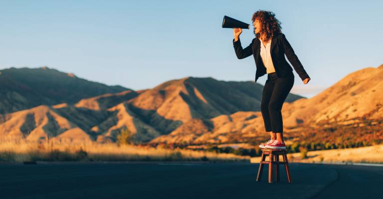 Zakenvrouw schreeuwt door een megaphone