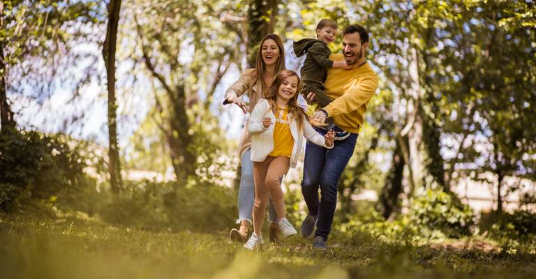 Een vader, moeder en 2 kinderen rennend door het bos